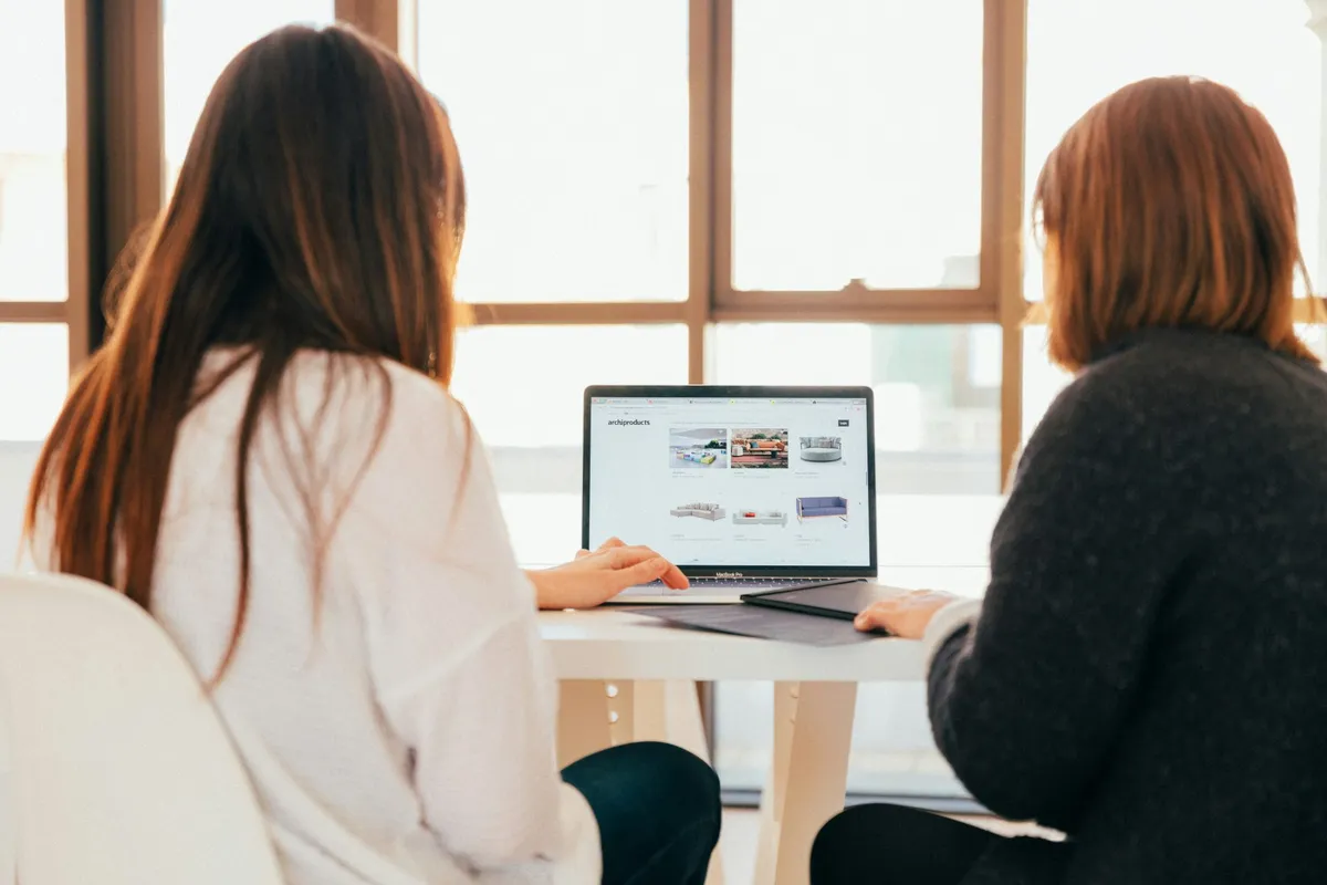 Two people reviewing a website together on a laptop in a bright office space